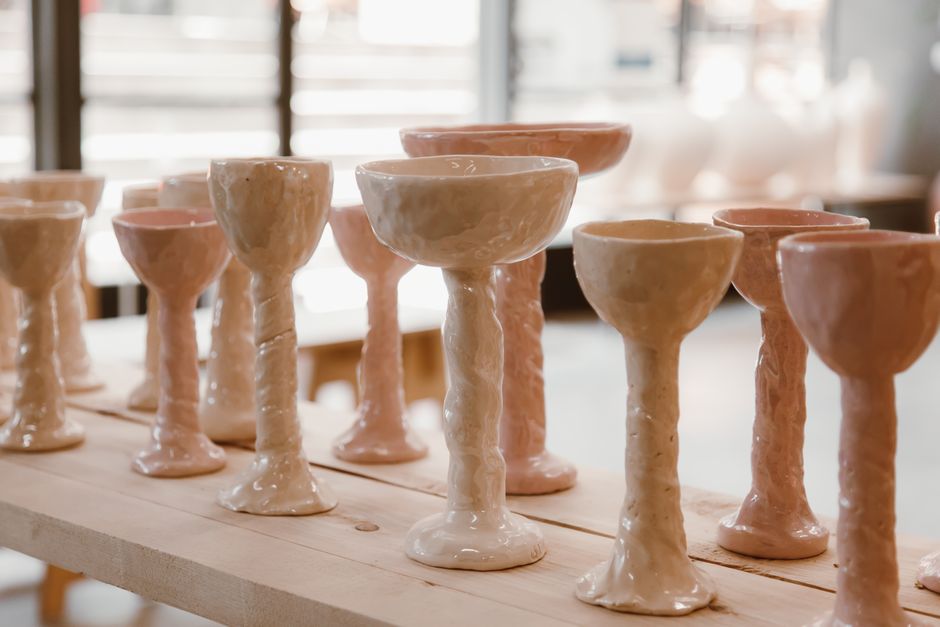 A beautiful display of handmade glazed pottery chalices arranged on a wooden table indoors.