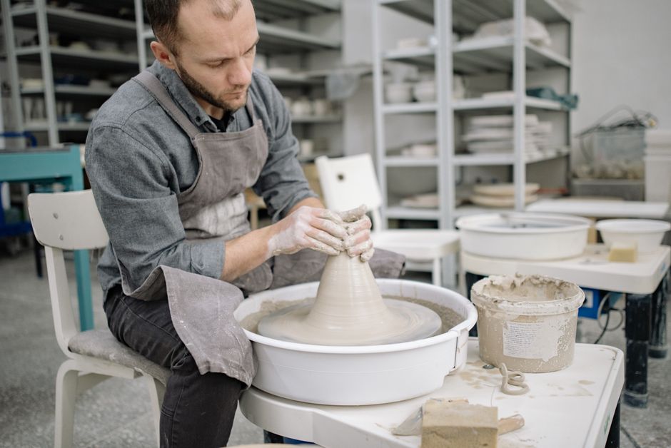 A focused potter crafting pottery on a wheel in an artisan workshop setting.