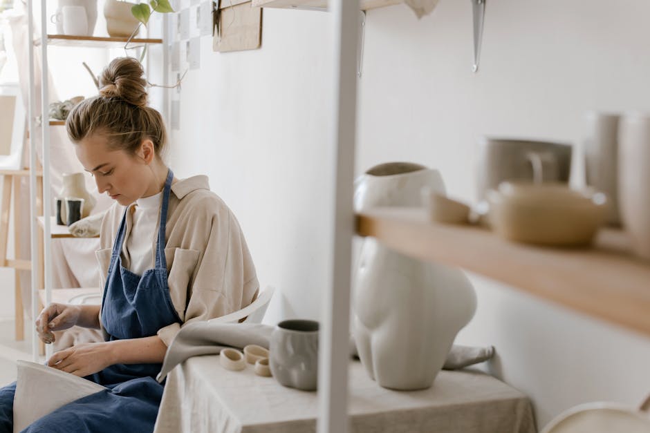 A woman artist carefully crafting pottery in a bright, modern ceramic studio.