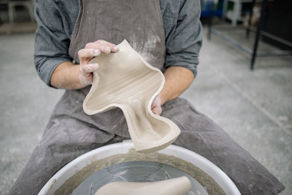 A craftsman skillfully molds clay on a pottery wheel, creating a unique ceramic piece.