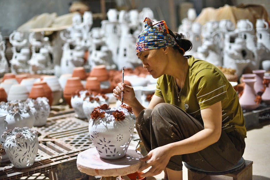 Focused artisan hand-painting intricate designs on ceramic vases in a pottery workshop.